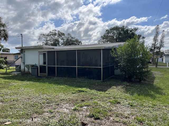 back of property with a sunroom and a yard