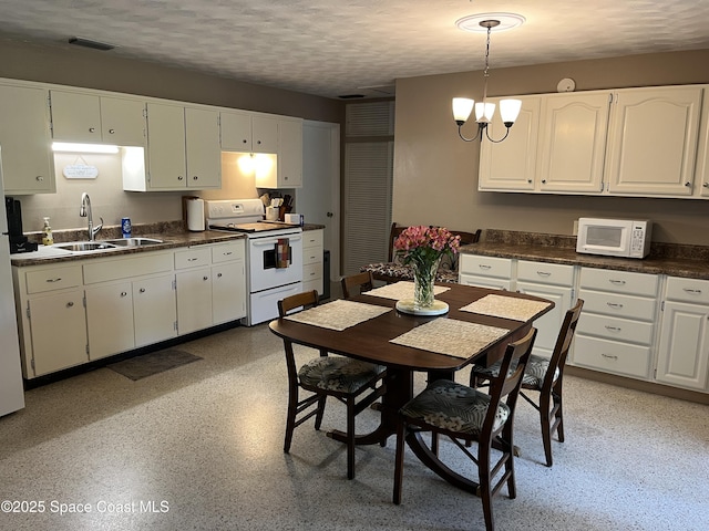 kitchen featuring sink, white appliances, white cabinetry, a notable chandelier, and a textured ceiling