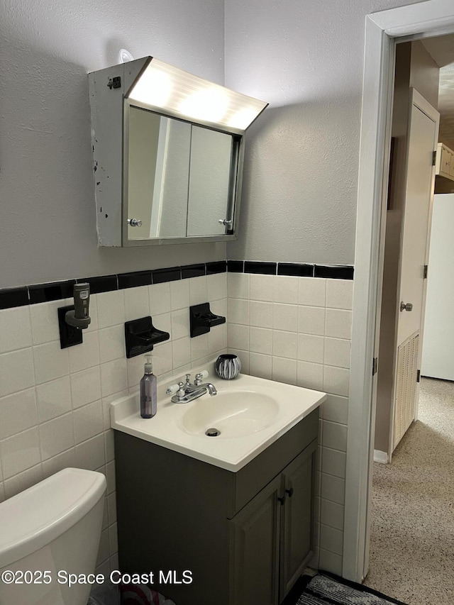 bathroom with vanity, tile walls, and toilet