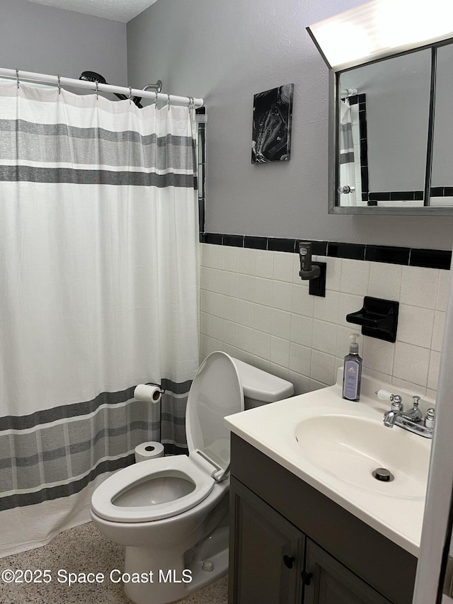 bathroom with vanity, toilet, and tile walls