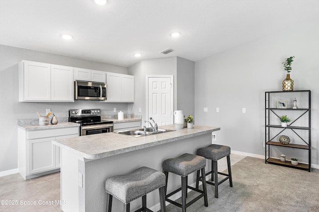 kitchen featuring white cabinetry, sink, stainless steel appliances, and an island with sink