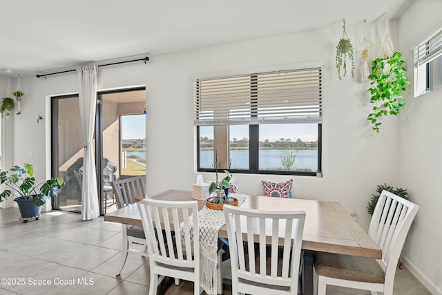 dining room with light tile patterned flooring and a water view