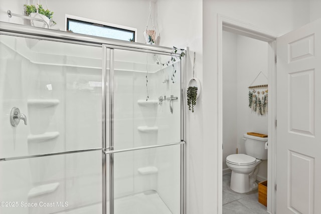 bathroom with tile patterned flooring, a shower with shower door, and toilet