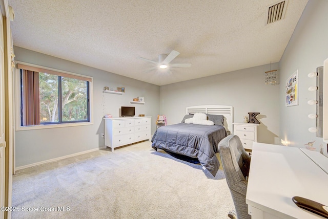 bedroom with ceiling fan, light carpet, and a textured ceiling