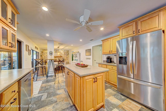 kitchen with ceiling fan, stainless steel appliances, a kitchen island, and light brown cabinets