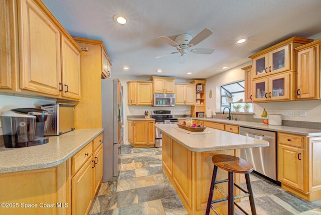 kitchen featuring sink, ceiling fan, appliances with stainless steel finishes, a kitchen breakfast bar, and a kitchen island