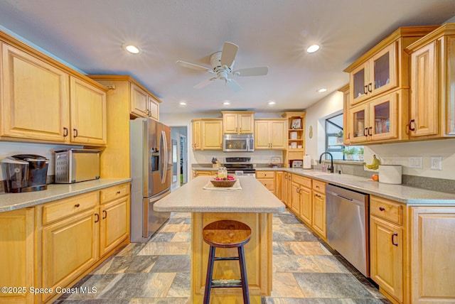 kitchen featuring sink, a breakfast bar area, light brown cabinets, appliances with stainless steel finishes, and a kitchen island