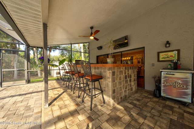 exterior space with a bar, a lanai, and ceiling fan