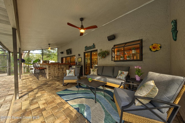 view of patio with ceiling fan, an outdoor living space, an outdoor bar, and glass enclosure