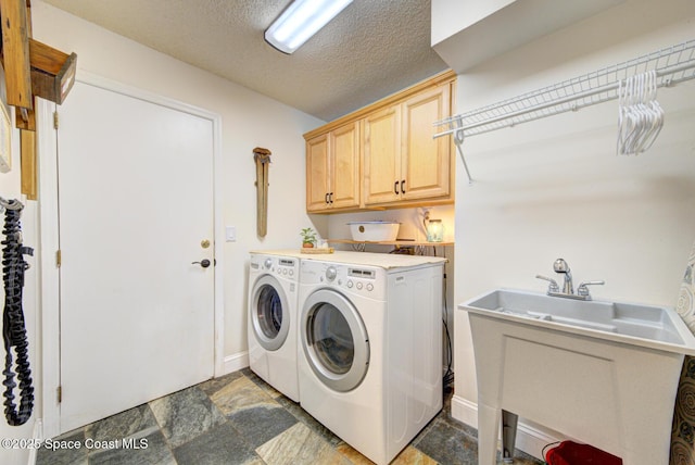 laundry room with cabinets, sink, washer and dryer, and a textured ceiling