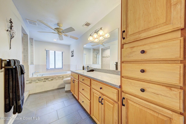 bathroom with toilet, vanity, tiled tub, ceiling fan, and tile patterned flooring