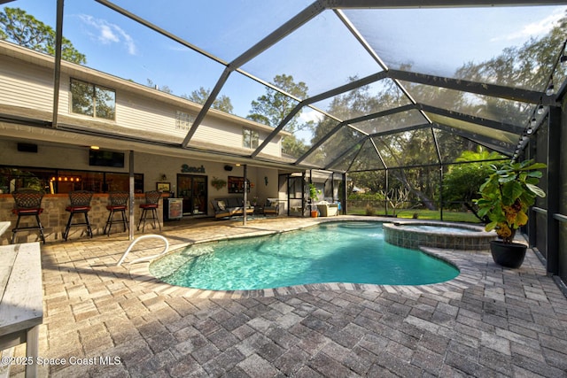 view of pool featuring a patio area, an in ground hot tub, glass enclosure, and exterior bar