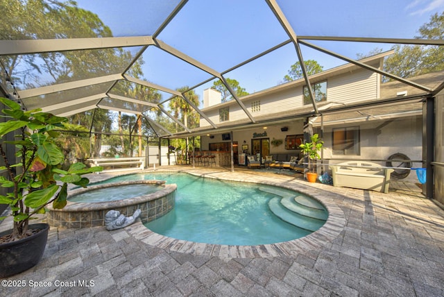 view of pool with a patio area, a lanai, an in ground hot tub, exterior bar, and an outdoor hangout area