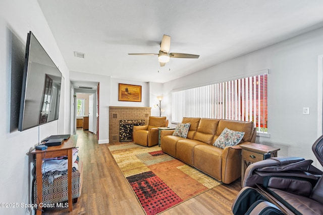 living room featuring hardwood / wood-style flooring, a brick fireplace, and ceiling fan