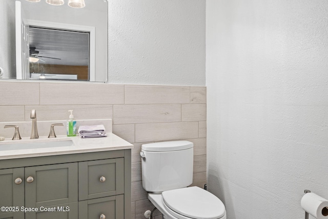 bathroom with vanity, tile walls, and toilet