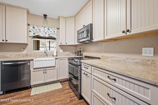 kitchen featuring sink, dark wood-type flooring, stainless steel appliances, and cream cabinetry