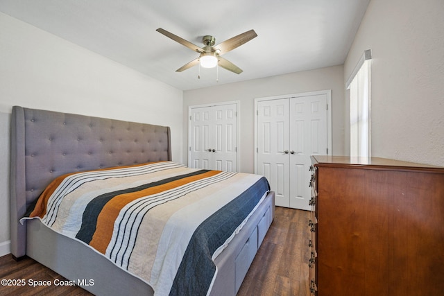 bedroom with ceiling fan, two closets, and dark hardwood / wood-style flooring