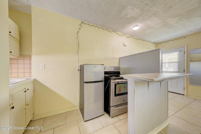 kitchen with light tile patterned flooring, a breakfast bar area, kitchen peninsula, stainless steel appliances, and a textured ceiling