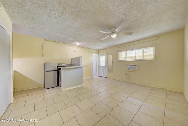 interior space featuring light tile patterned flooring, a textured ceiling, an AC wall unit, appliances with stainless steel finishes, and ceiling fan