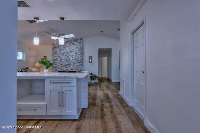 kitchen featuring white cabinetry, crown molding, vaulted ceiling, ceiling fan, and light hardwood / wood-style floors