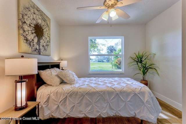 bedroom featuring ceiling fan, wood-type flooring, and a textured ceiling