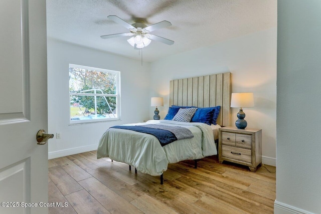 bedroom featuring ceiling fan, light hardwood / wood-style floors, and a textured ceiling