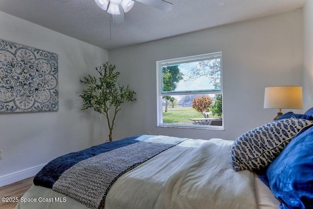 bedroom featuring wood-type flooring, ceiling fan, and a textured ceiling