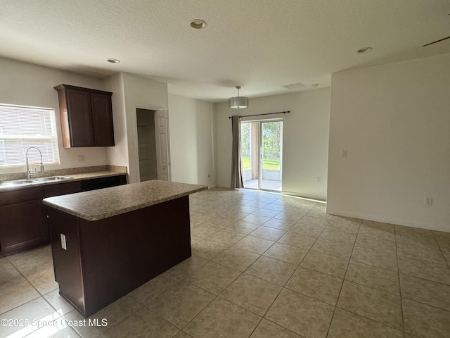 kitchen featuring dark brown cabinetry, sink, a textured ceiling, light tile patterned floors, and a kitchen island