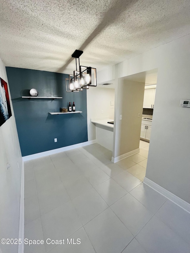 unfurnished dining area featuring a textured ceiling and light tile patterned floors