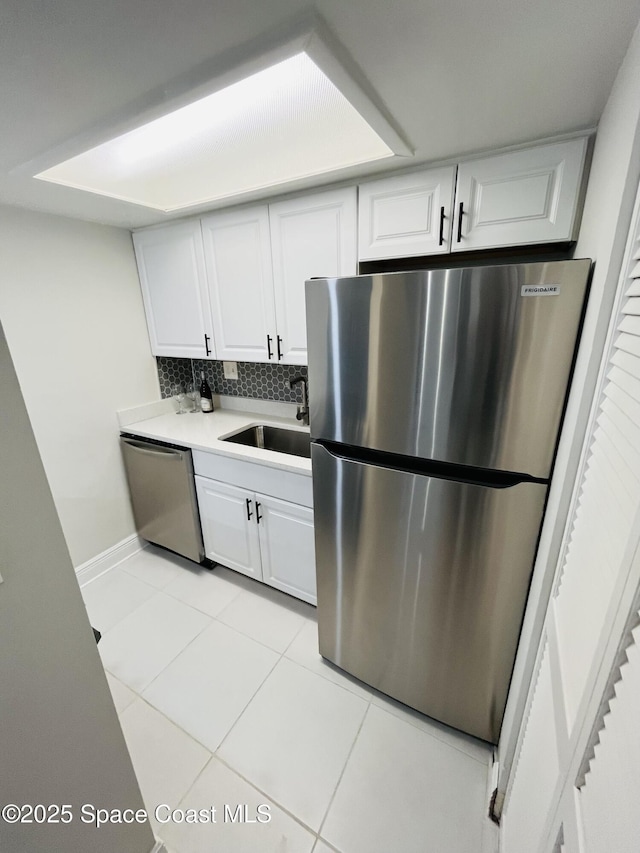 kitchen featuring white cabinetry, sink, light tile patterned flooring, and appliances with stainless steel finishes