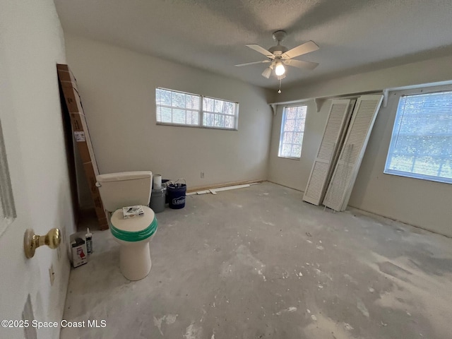 unfurnished bedroom with ceiling fan and a textured ceiling