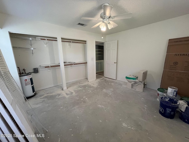 unfurnished bedroom with concrete flooring, a textured ceiling, electric water heater, two closets, and ceiling fan