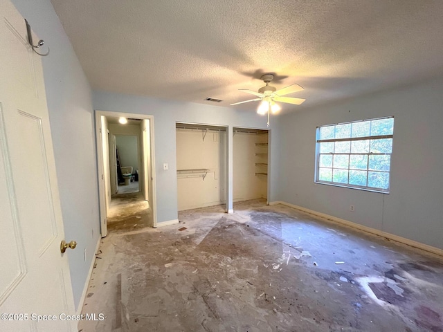 unfurnished bedroom featuring ceiling fan, two closets, and a textured ceiling