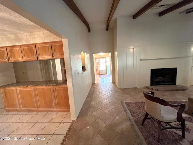 kitchen with beam ceiling, a high ceiling, a brick fireplace, and light tile patterned floors