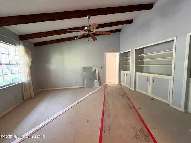 empty room featuring lofted ceiling with beams and ceiling fan