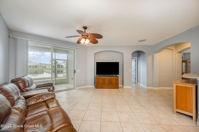 tiled living room with ceiling fan and a textured ceiling