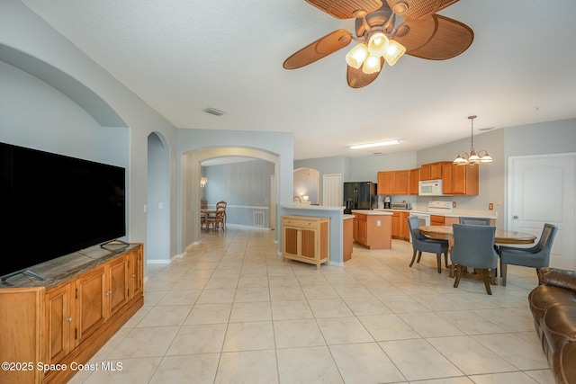 kitchen with pendant lighting, light tile patterned floors, white appliances, and ceiling fan with notable chandelier