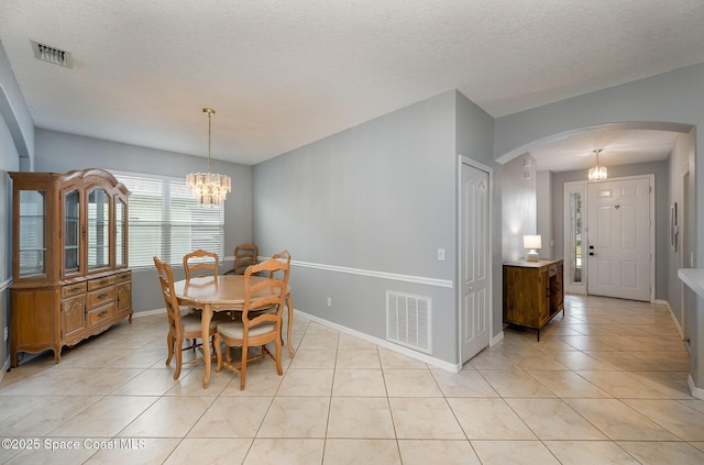 dining space with light tile patterned flooring, a chandelier, and a textured ceiling