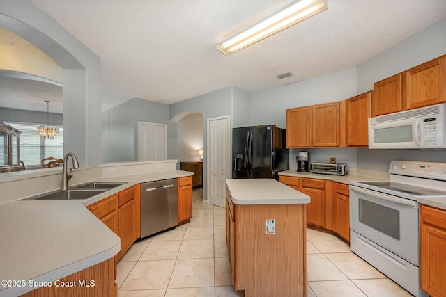 kitchen featuring a kitchen island, decorative light fixtures, sink, a notable chandelier, and white appliances