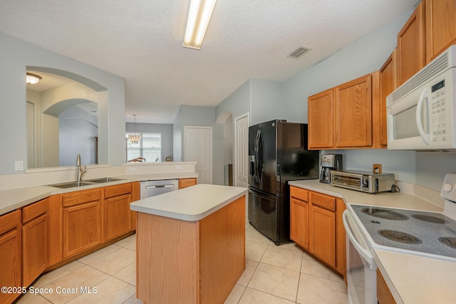 kitchen with light tile patterned flooring, white appliances, sink, and a kitchen island