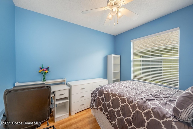 bedroom with ceiling fan, a textured ceiling, and light wood-type flooring