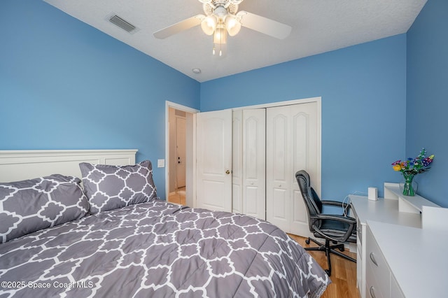 bedroom featuring ceiling fan, light hardwood / wood-style floors, a closet, and a textured ceiling