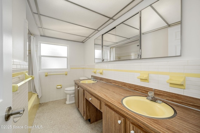 full bathroom with shower / bathtub combination with curtain, vanity, toilet, and tile walls