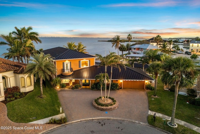 view of front of home featuring a balcony, a water view, and a yard