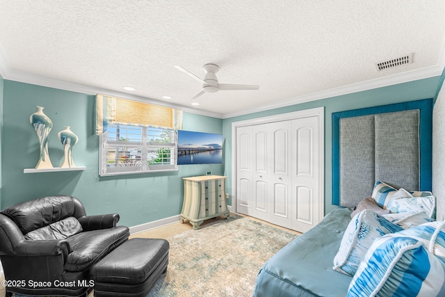 living room featuring ceiling fan, ornamental molding, and a textured ceiling