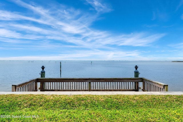 view of dock featuring a lawn and a water view