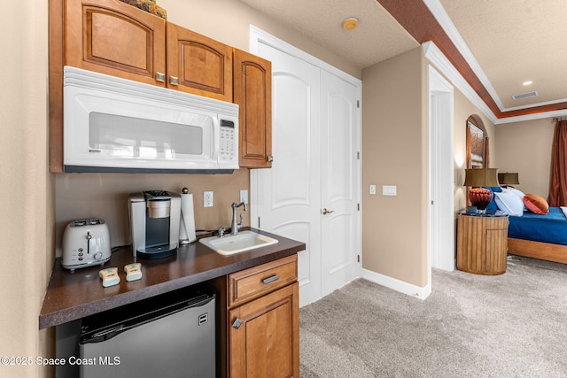 bar featuring sink, dishwashing machine, ornamental molding, light carpet, and a textured ceiling