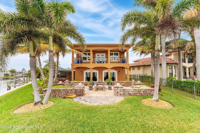 rear view of house with a water view, a balcony, a yard, and a patio area