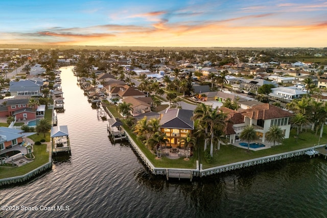 aerial view at dusk featuring a water view