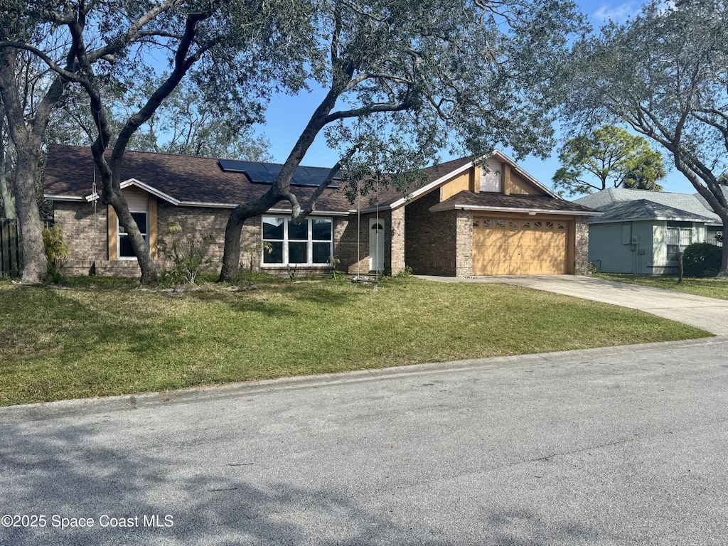 view of front of property with a garage, a front yard, and solar panels